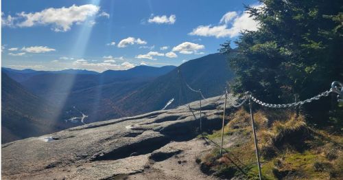 A trail with a chain chained fence overlooking a valley.