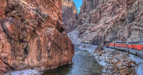 Royal Gorge train travels along a snowy river through the steep, red rock canyons of Colorado.