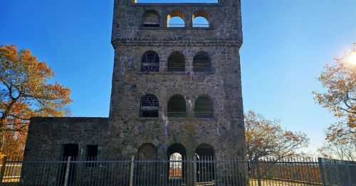 A stone castle enclosed by a short fence.