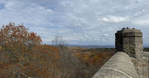 A castle wall overlooking a colorful fall forest scene.