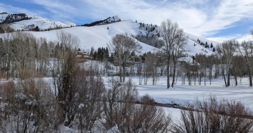 A winter landscape in Sun Valley, Idaho. Homes are nestled in the trees and next to snow-covered mountains.