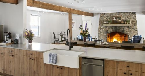 A kitchen and dining space with a lit stone fireplace.
