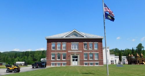 A red brick school house with a flag.