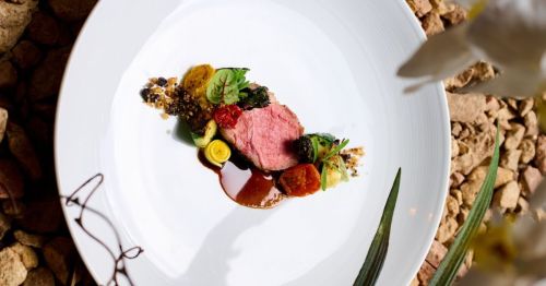 An elevated dish on a white plate on stone rocks.