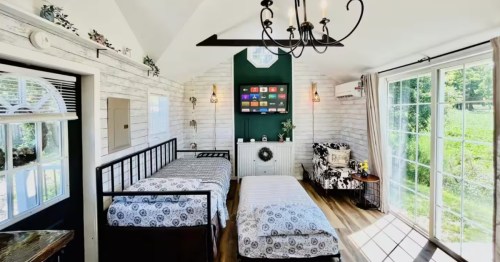 Cozy interior of the Selbyville Tiny House with two first-floor beds, a vaulted ceiling, and bright, rustic white paneling.