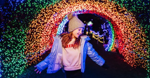 A preteen girl dances in front of a rainbow colored light archway at the Silverton Christmas Market in Silverton, Oregon.