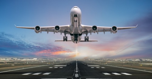 Commercial airplane taking off from a runway at sunrise.