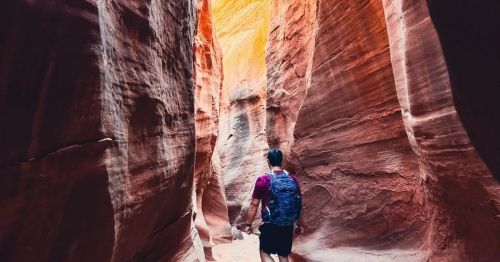 A hiker walking through a narrow passage inside Spooky Canyon in Utah.