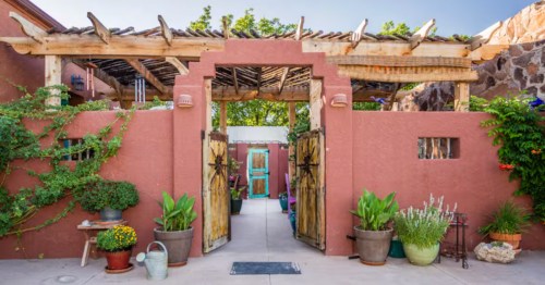 exterior of a casita in la mesa with double doors opening to a courtyard that leads to the turquoise and wood door