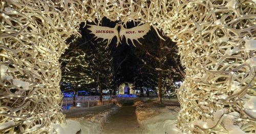 An arch made of elk antlers covered with dazzling Christmas lights at the entrance to Jackson, Wyoming's Town Square.