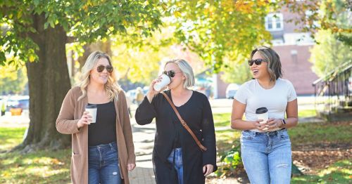 Three women walking down Main Street, drinking coffee on a pretty fall day.