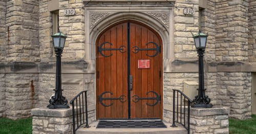 Grey stone walls surround two dark brown wooden archway doors