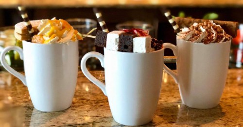 three different hot chocolates in white mugs have toppings and sit on a bar at the chanler cliff walk in newport rhode island