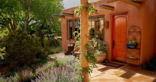 exterior of a terrecotta colored bungalow with a lavender garden and greenery on a sunny day in New Mexico