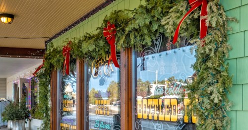 Green Christmas garlands with red ribbons and colorful lights decorate a storefront window in Nissa, Minnesota.