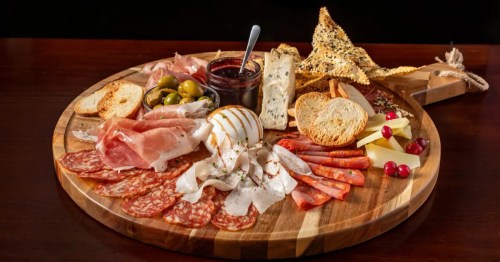 Large charcuterie board with prosciutto, salami, burrata, olives, and gourmet cheeses.