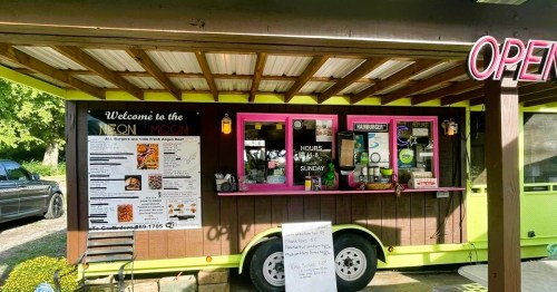 A food-truck-style restaurant in Arkansas featuring a menu on the side, with a covered deck and outdoor seating.