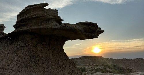 Dramatic toadstool rock formations silhouetted against a golden sunset and colorful sky. 