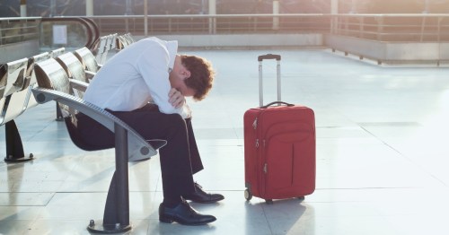 A tired traveler sits in an airport terminal waiting on a delayed flight.