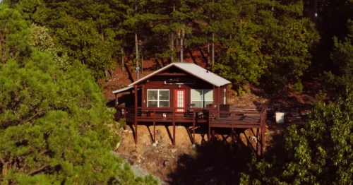 aerial shot of a small cabin with a wraparound deck surrounded by trees in tuskahoma oklahoma