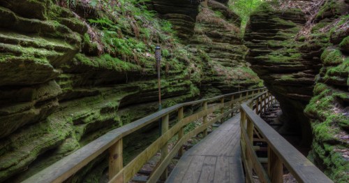 Green moss covered rocks on either side of a wooden foot bridge