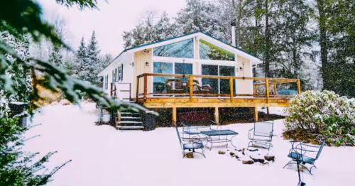 The exterior of a cabin in winter with a deck.