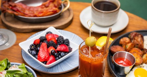 A close-up of various breakfast foods on a wooden table.