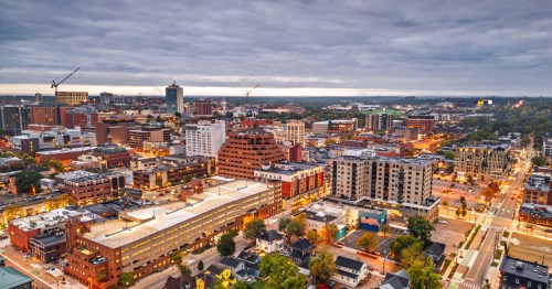 Illuminated buildings stand in a downtown with a cloudy sky.