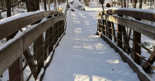 A snow covered wooden bridge.