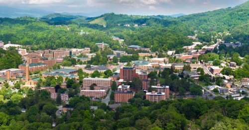 View of Boone, North Carolina, city buildings surrounded by green trees and the Blue Ridge Mountains
