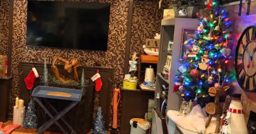 The interior of a living room decorated for Christmas, with stockings and a small neon tree.
