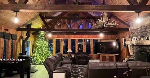 The spacious living area at the Inn at Embden Pond Airbnb rental in Embden, Maine is dimly lit and has a Christmas tree in the corner of the room.