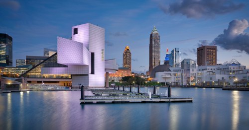 Illuminated buildings stand on a harbor at twilight on a cloudy night.