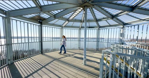 Girl standing inside a covered observation deck that looks like a bird cage, overlooking the water at Lake Red Rock Iowa