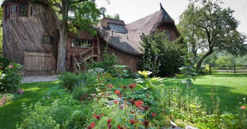 The exterior of a castle-like wooden Airbnb surrounded by trees and shrubs.