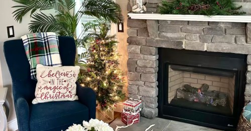 A close-up of a fireplace and small Christmas tree in a room decorated for Christmas
