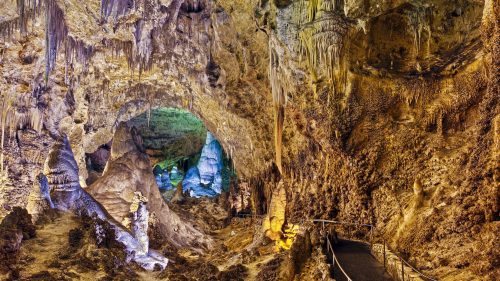 A colorful cave interior with stalactites and stalagmites, featuring a winding pathway through the rock formations.