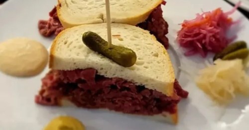 A sandwich with a pickle and toothpick stuck through it.