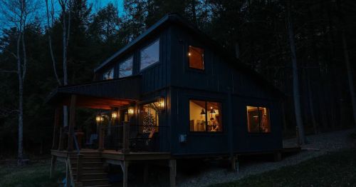 An external shot of the Hemlock Hideaway in Otego New York. The interior of the home is well-lit.