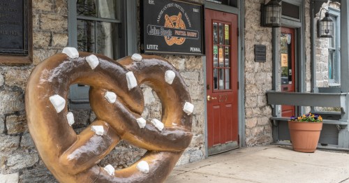 A large, salted pretzel statue sits outside the historic stone storefront of Julius Sturgis Pretzel Bakery in Lititz.