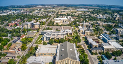 A downtown city stretches to a blue sky horizon with green trees throughout.