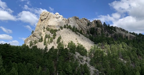 Presidential Loop Trail, Keystone. Mount Rushmore's carved faces are visible atop the steep, forested, rocky mountain slope.