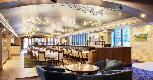 Looking into a classy dining room with a sign above the entrance saying "Riverside Grill."