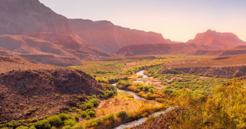 Sunlit desert mountains and a winding river cutting through Big Bend Ranch State Park.
