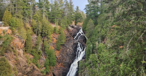 Green and yellow trees flank a tall waterfall