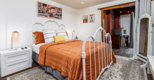 A bright orange bedspread on a bed placed on top of an oversized rug