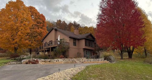 Orange and red trees surround a brown cabin home in Galena