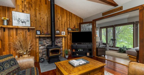 Living room with wood paneled walls and a black fireplace
