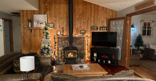 Wood paneled living room area with a fireplace and television