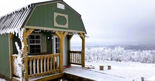 Cozy winter cabin in Arkansas perched on a hill after heavy snowfall. .